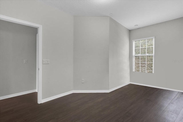 empty room with a textured ceiling and dark wood-type flooring