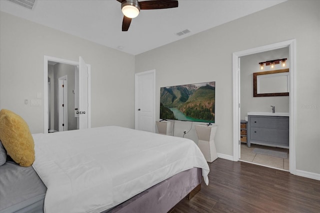 bedroom featuring dark hardwood / wood-style floors, ceiling fan, ensuite bathroom, and sink