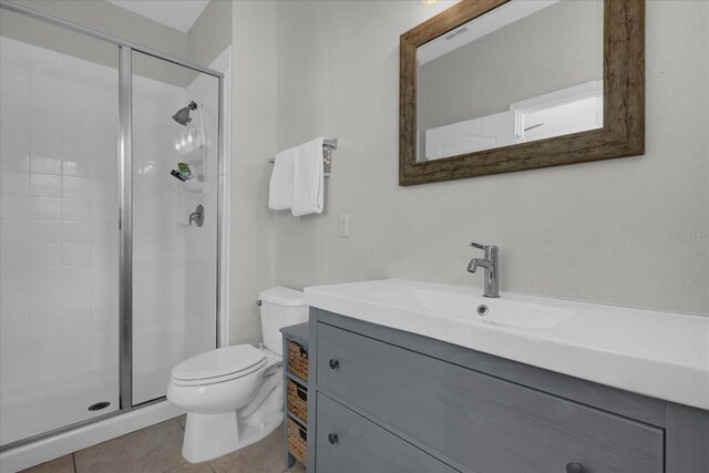 bathroom with vanity, a shower with shower door, toilet, and tile patterned floors