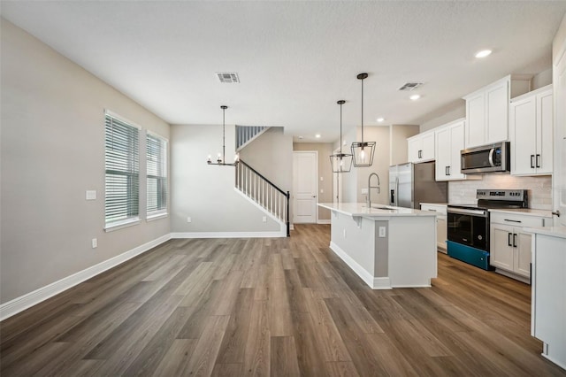 kitchen featuring white cabinetry, a kitchen island with sink, pendant lighting, and stainless steel appliances