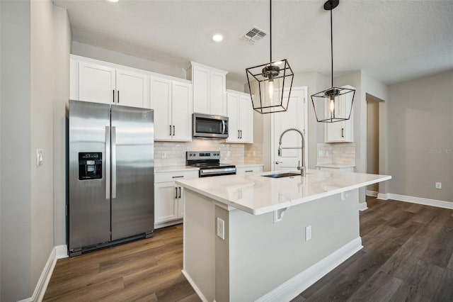 kitchen featuring stainless steel appliances, sink, a center island with sink, white cabinets, and hanging light fixtures