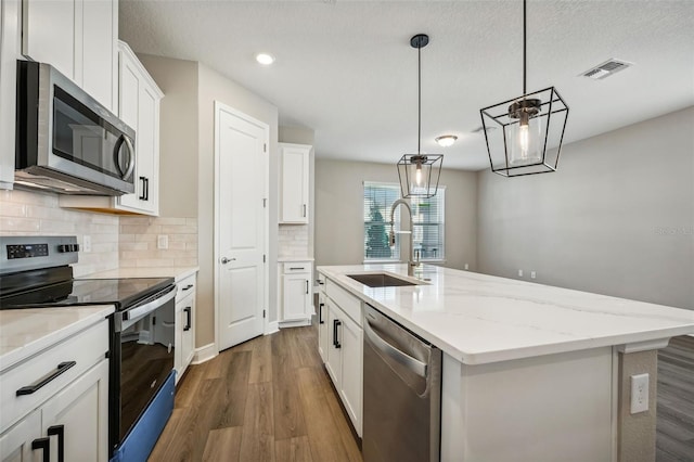 kitchen featuring sink, dark hardwood / wood-style floors, a kitchen island with sink, white cabinets, and appliances with stainless steel finishes