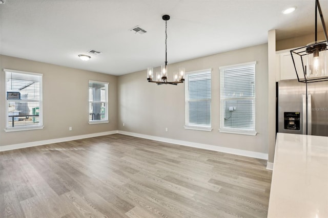 unfurnished dining area featuring a chandelier and light hardwood / wood-style floors