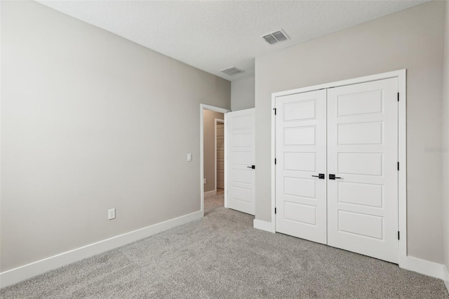 unfurnished bedroom featuring a closet, light colored carpet, and a textured ceiling