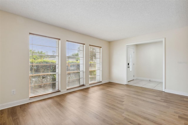 spare room with a textured ceiling and light hardwood / wood-style floors