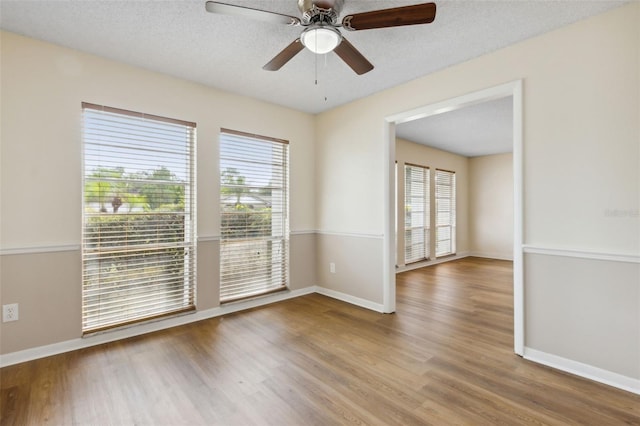 unfurnished room with hardwood / wood-style floors, plenty of natural light, ceiling fan, and a textured ceiling