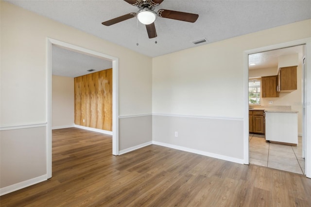 spare room featuring ceiling fan, a textured ceiling, and light wood-type flooring