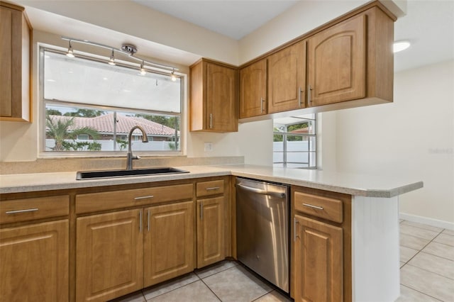 kitchen featuring kitchen peninsula, stainless steel dishwasher, a healthy amount of sunlight, sink, and light tile patterned flooring