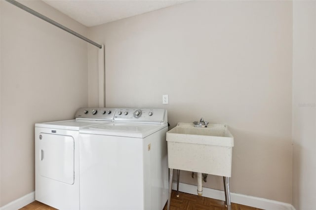 clothes washing area with parquet flooring, sink, and washing machine and clothes dryer