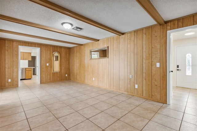 interior space featuring beam ceiling, a textured ceiling, and wooden walls