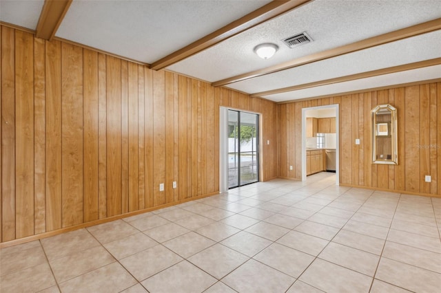 tiled spare room with beam ceiling, wooden walls, and a textured ceiling