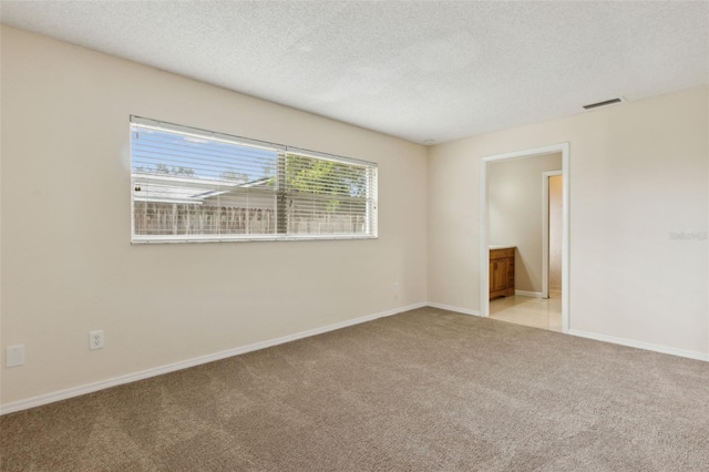 carpeted spare room featuring a textured ceiling