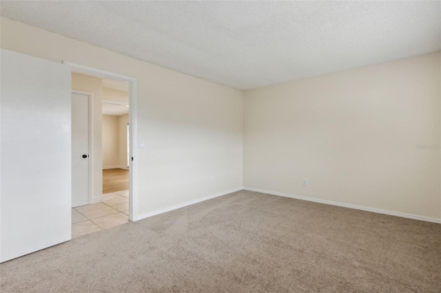 unfurnished room featuring a textured ceiling and light colored carpet