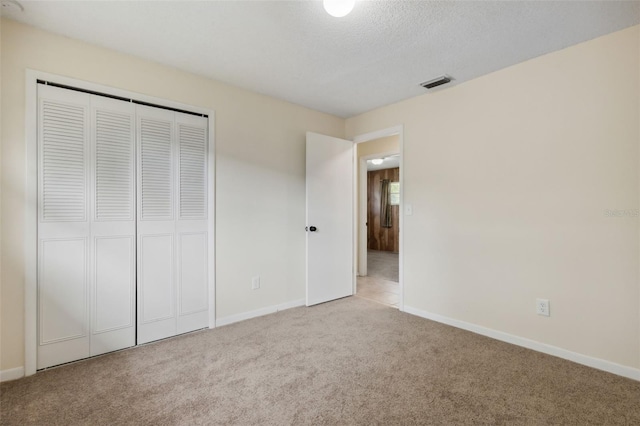 unfurnished bedroom with a closet, light colored carpet, and a textured ceiling