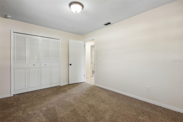 unfurnished bedroom featuring light carpet, a textured ceiling, and a closet