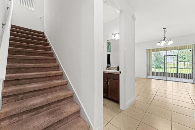 stairs with tile patterned flooring, an inviting chandelier, and sink