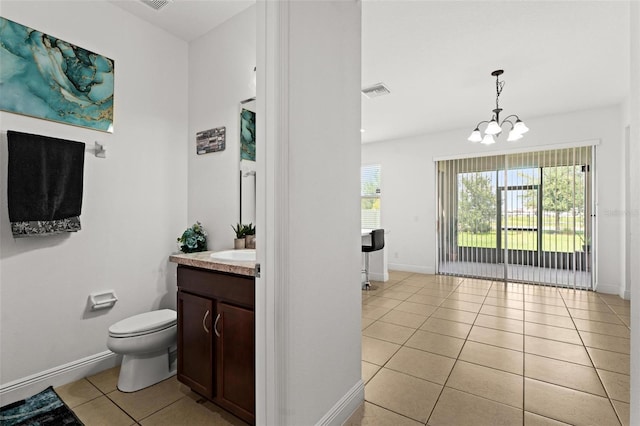 bathroom featuring tile patterned flooring, a chandelier, vanity, and toilet