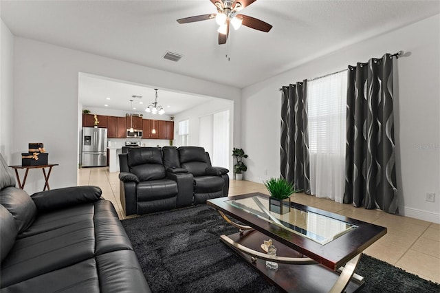 living room with ceiling fan with notable chandelier and light tile patterned floors