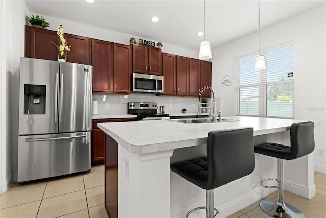 kitchen with pendant lighting, a kitchen island with sink, sink, a kitchen bar, and appliances with stainless steel finishes