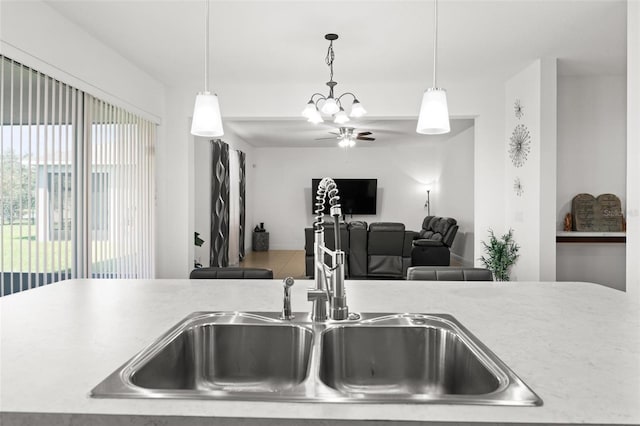 kitchen featuring ceiling fan with notable chandelier, hanging light fixtures, and sink