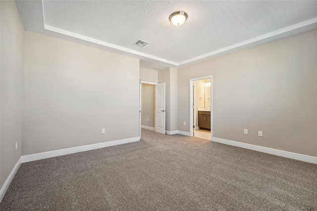 unfurnished bedroom with a textured ceiling, light colored carpet, and ensuite bath