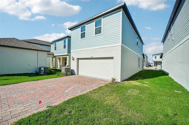 rear view of house with a lawn, cooling unit, and a garage