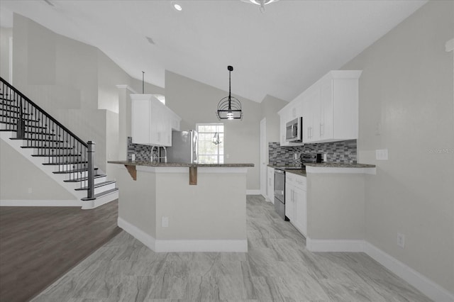 kitchen featuring white cabinets, kitchen peninsula, stainless steel appliances, a kitchen breakfast bar, and vaulted ceiling