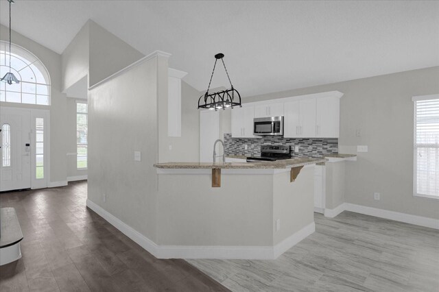 kitchen featuring white cabinetry, appliances with stainless steel finishes, plenty of natural light, and hanging light fixtures