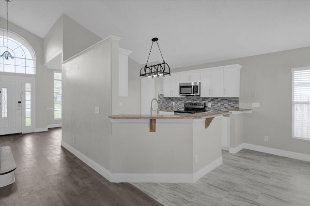 kitchen with white cabinets, stainless steel appliances, an inviting chandelier, decorative backsplash, and a breakfast bar area