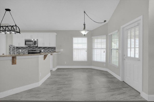 kitchen with pendant lighting, a breakfast bar, white cabinets, lofted ceiling, and appliances with stainless steel finishes