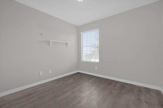 unfurnished room featuring vaulted ceiling, baseboards, and dark wood finished floors