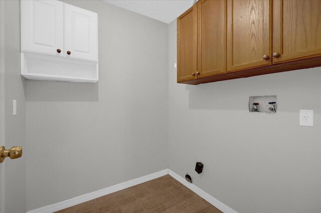 washroom featuring hookup for a washing machine, hardwood / wood-style flooring, a textured ceiling, and cabinets