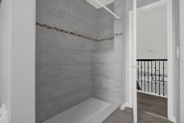 bathroom featuring hardwood / wood-style flooring and a tile shower