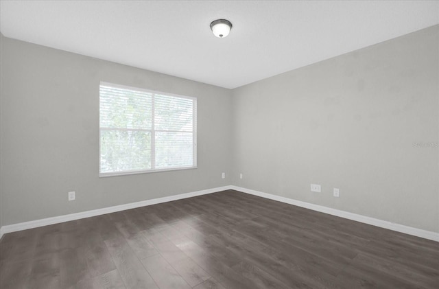 unfurnished room with dark wood finished floors and baseboards