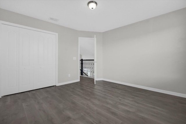 unfurnished bedroom with baseboards, wood finished floors, and a closet