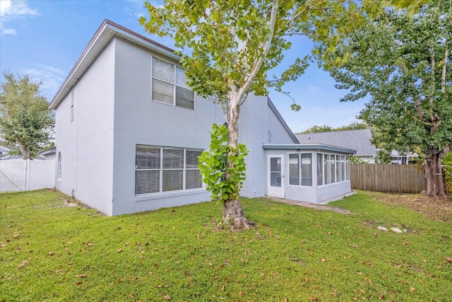 back of house featuring a sunroom and a lawn