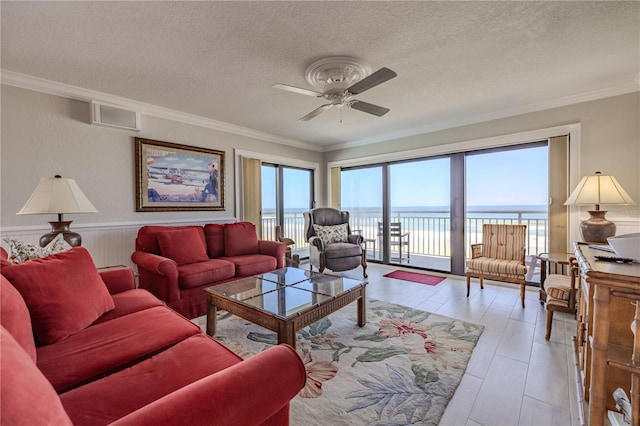 living room with a textured ceiling, a water view, ornamental molding, and ceiling fan