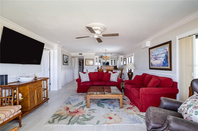 living room featuring light wood-type flooring, ceiling fan with notable chandelier, and crown molding