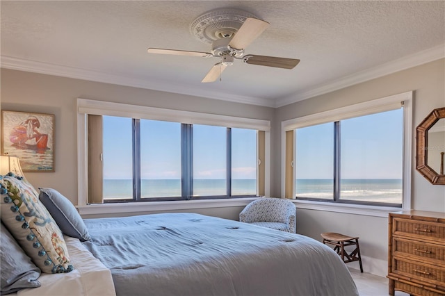 bedroom with ceiling fan, a textured ceiling, ornamental molding, and a water view