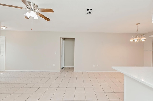 spare room with ceiling fan with notable chandelier and light tile patterned flooring