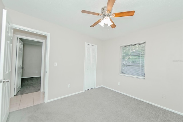 unfurnished bedroom featuring ceiling fan, light carpet, and a closet