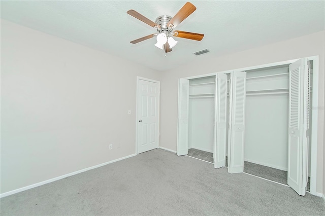 unfurnished bedroom featuring ceiling fan, light carpet, and multiple closets