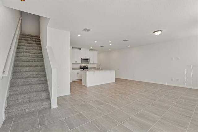 unfurnished living room featuring light tile patterned flooring and sink