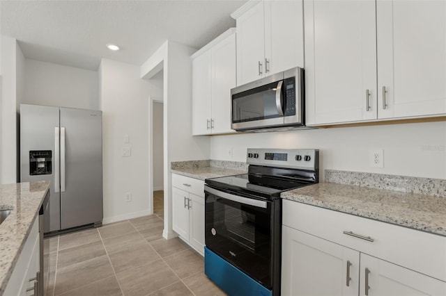 kitchen featuring stainless steel appliances, light tile patterned floors, white cabinets, and light stone counters