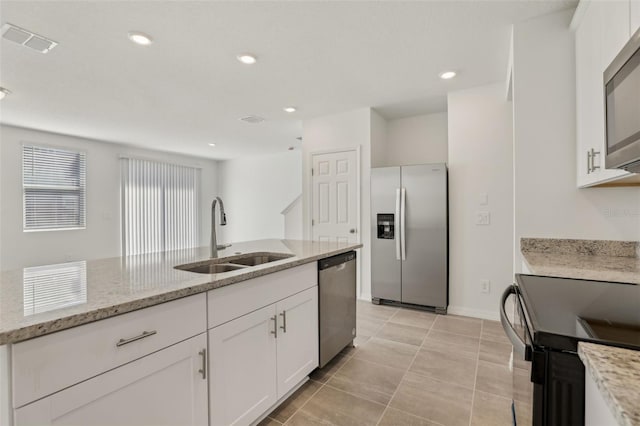 kitchen with light tile patterned flooring, white cabinetry, sink, stainless steel appliances, and light stone countertops