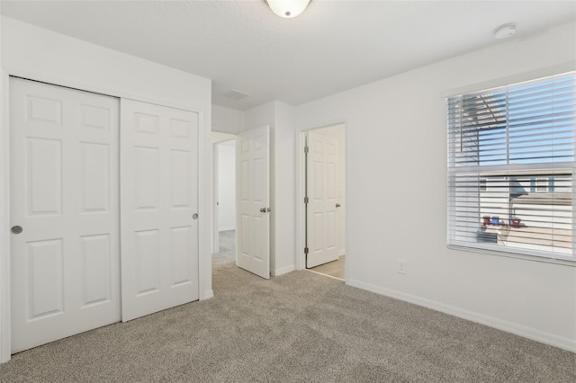 unfurnished bedroom with light colored carpet and a closet