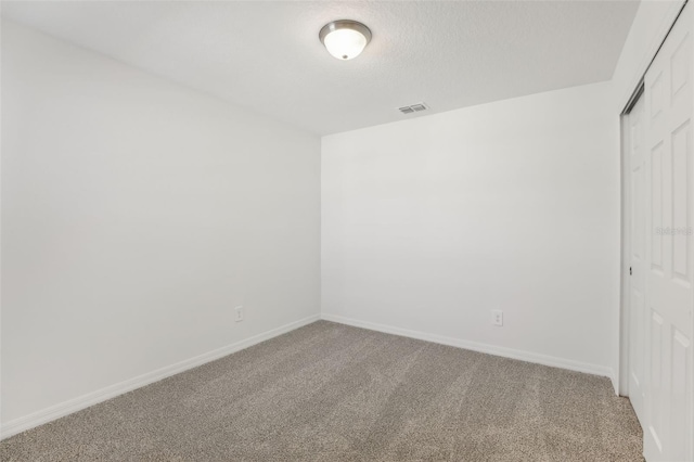 carpeted empty room featuring a textured ceiling