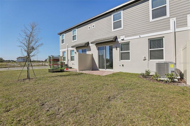 rear view of property featuring a patio, a lawn, a trampoline, and central air condition unit