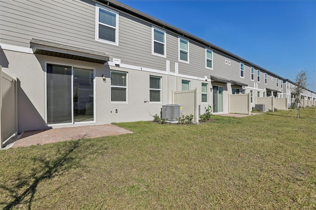 back of house featuring central AC unit and a lawn