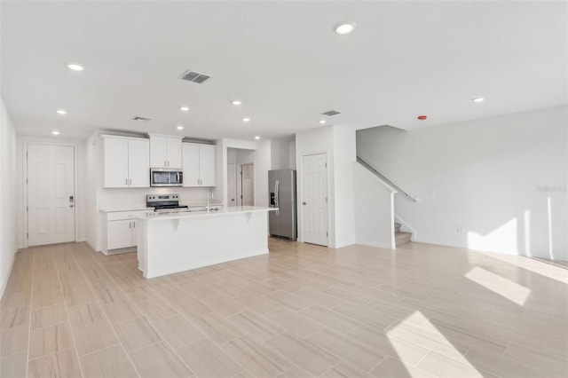 kitchen with white cabinetry, stainless steel appliances, and an island with sink